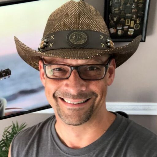 A smiling man in his 40s wearing a cowboy hat.